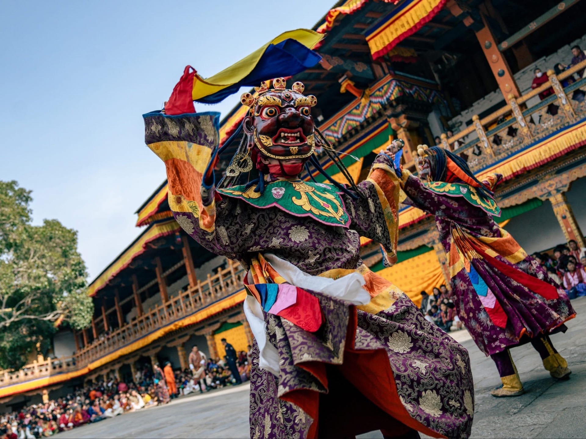 Masked Cham dancers performing in a dzong courtyard during a tshechu