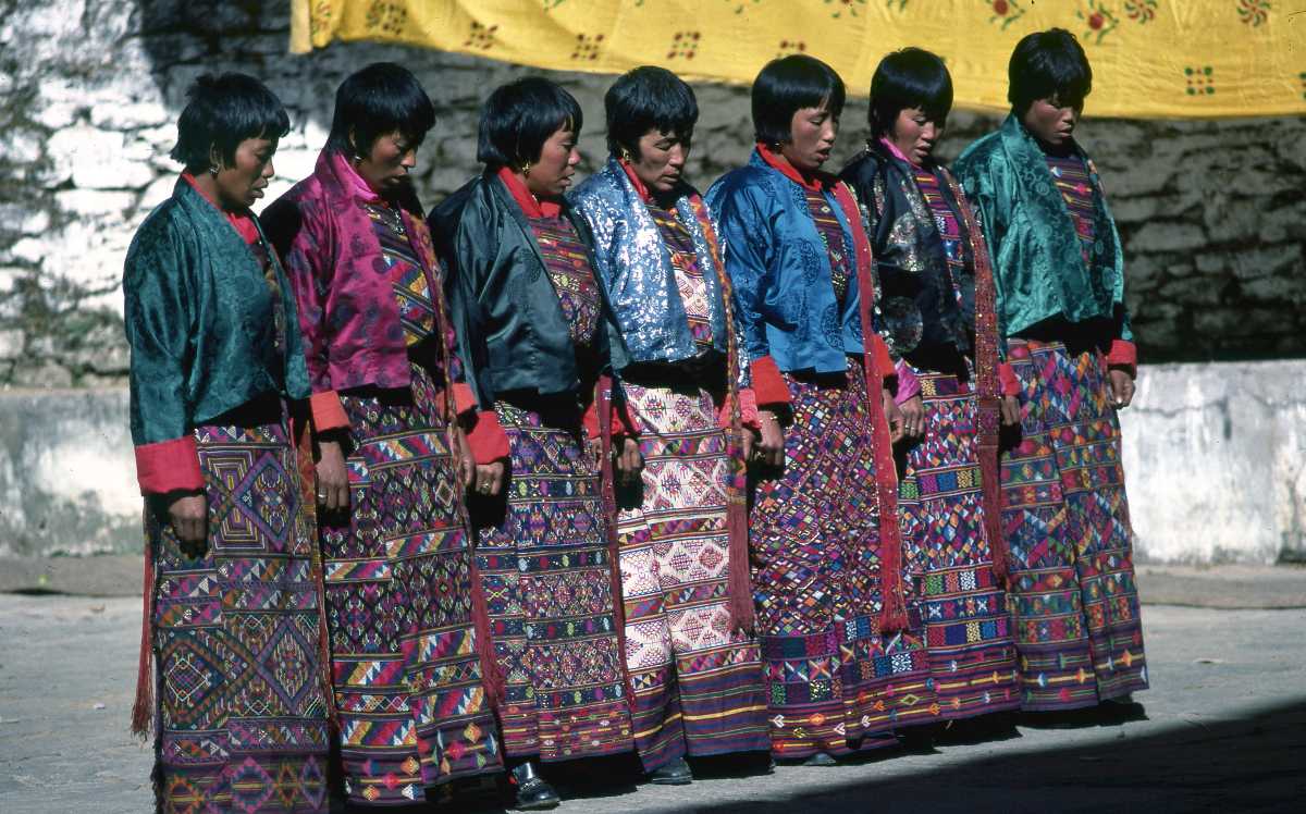 Bhutanese women in vibrant traditional kira and kabney performing together outdoors